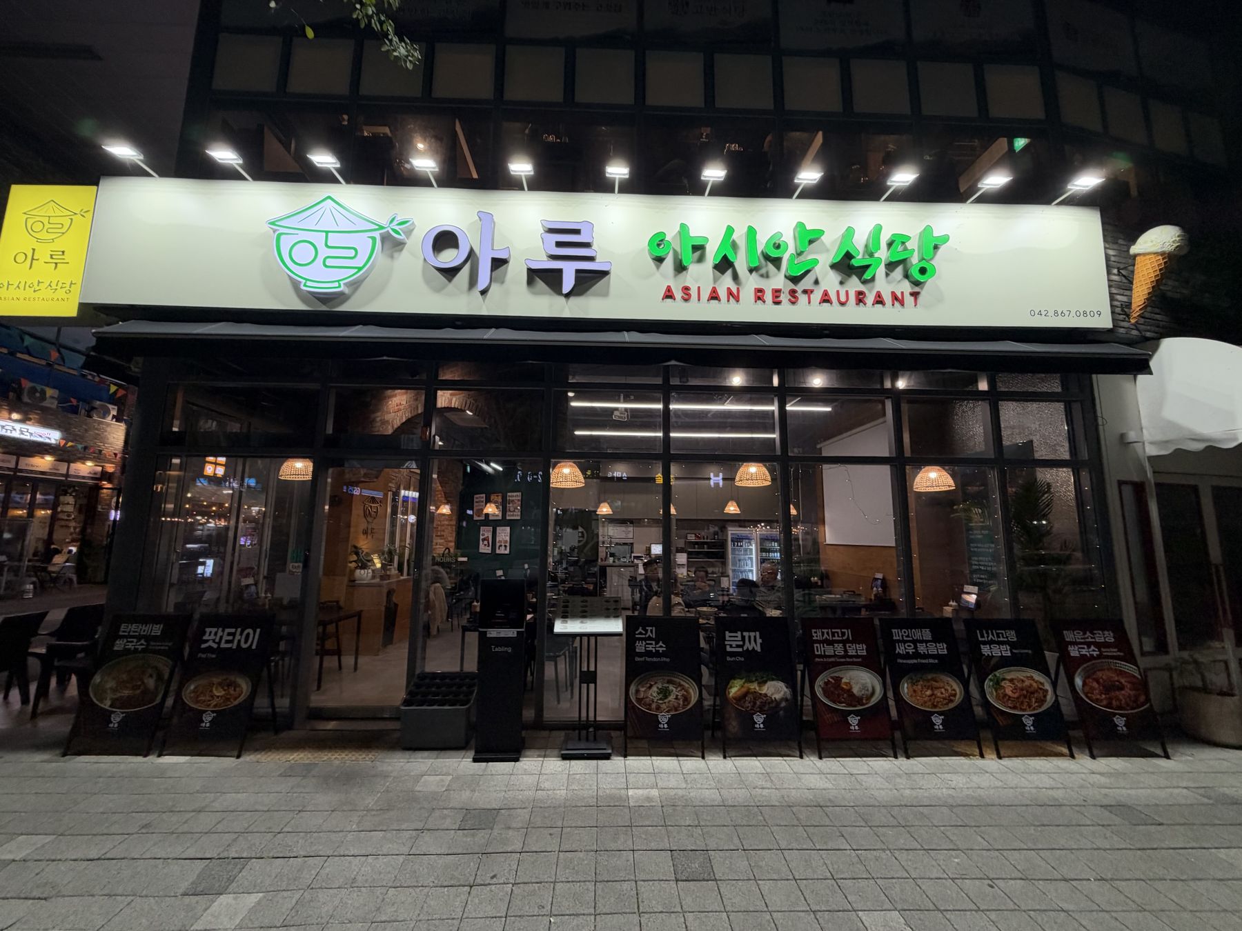 저녁에 불이 켜진 아루 아시안식당 외관과 간판
